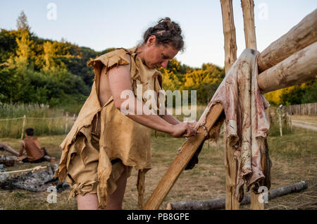 Albersdorf, Germany. 24th July, 2018. A woman scrapes meat remains from a deer skin. Around 80 men, women and children met in Alberdorf in the district of Dithmarschen under the motto 'largest Stone Age meeting since the Stone Age'. Credit: Axel Heimken/dpa/Alamy Live News Stock Photo