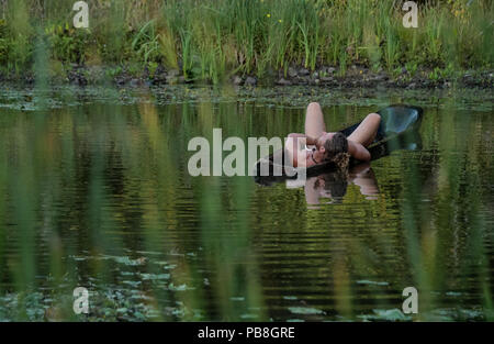 Albersdorf, Germany. 24th July, 2018. A man rests in a self-built dugout boat. Around 80 men, women and children met in Alberdorf in the district of Dithmarschen under the motto 'largest Stone Age meeting since the Stone Age'. Credit: Axel Heimken/dpa/Alamy Live News Stock Photo