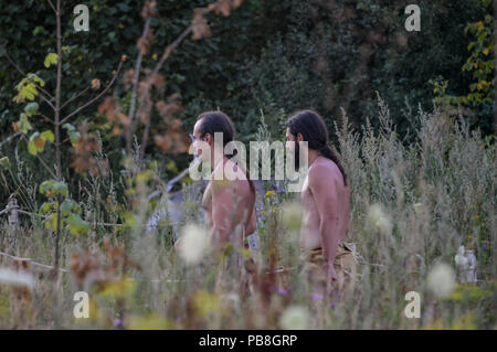 Albersdorf, Germany. 24th July, 2018. Two men walk through the tall grass of a meadow. Around 80 men, women and children met in Alberdorf in the district of Dithmarschen under the motto 'largest Stone Age meeting since the Stone Age'. Credit: Axel Heimken/dpa/Alamy Live News Stock Photo