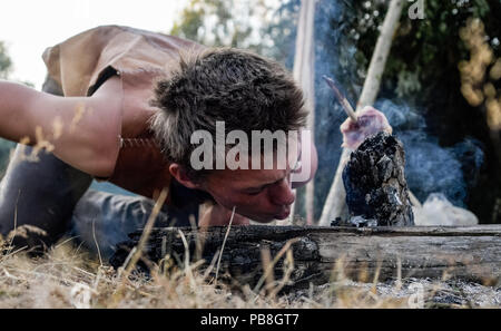 Albersdorf, Germany. 24th July, 2018. A man tries to light a fire with his breath. Around 80 men, women and children met in Alberdorf in the district of Dithmarschen under the motto 'largest Stone Age meeting since the Stone Age'. Credit: Axel Heimken/dpa/Alamy Live News Stock Photo