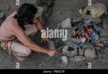 Albersdorf, Germany. 24th July, 2018. A man hardens wood in a fire. Around 80 men, women and children met in Alberdorf in the district of Dithmarschen under the motto 'largest Stone Age meeting since the Stone Age'. Credit: Axel Heimken/dpa/Alamy Live News Stock Photo