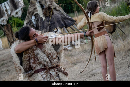 Albersdorf, Germany. 24th July, 2018. Two women practice archery with a self-made bow. Around 80 men, women and children met in Alberdorf in the district of Dithmarschen under the motto 'largest Stone Age meeting since the Stone Age'. Credit: Axel Heimken/dpa/Alamy Live News Stock Photo