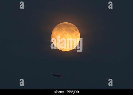 North London. London. UK 26 July 2018 - A British Airways plane flying below the Blood Moon in North London, as the longest lunar eclipse of the century, set for Friday 27 July 2018, has already started turning the celestial body a deep scarlet colour. The Blood Moon will be the UK’s first chance to see a major eclipse in 2018, and according to NASA’s Moon experts at the Goddard Space Centre, the eclipse will last around one hour and 43 minutes.  Credit: Dinendra Haria/Alamy Live News