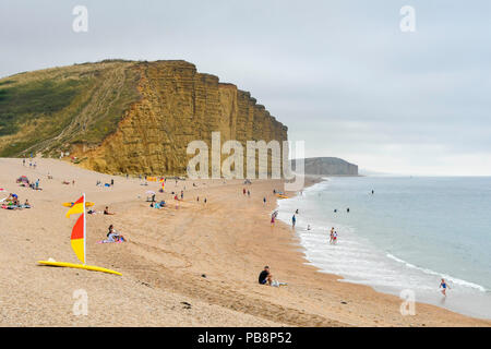 West Bay, Dorset, UK.  27th June 2018. UK Weather.  The beach is quieter on an overcast day at the seaside resort of West Bay in Dorset as temperatures drop as the heatwave ends.  Picture Credit: Graham Hunt/Alamy Live News Stock Photo