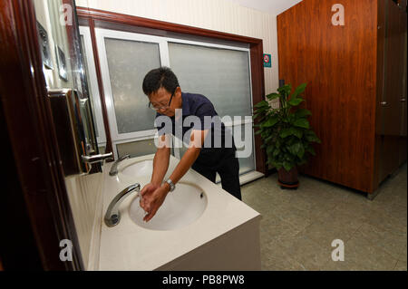 (180727) -- HOHHOT, July 27, 2018 (Xinhua) -- A man washes hands at an upgraded toilet in the Huimin District of Hohhot, capital of north China's Inner Mongolia Autonomous Region, July 27, 2018. In order to better serve people, toilets in the Huimin District of Hohhot have been upgraded to a combination of public toilets, bookstores, tea houses, convenience stores and self-service banks since 2017. A total of 31 upgraded toilets have been constructed and 99 more will be finished by the end of this year. (Xinhua/Peng Yuan) Stock Photo