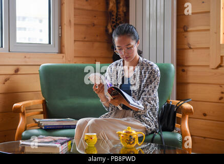 (180727) -- HOHHOT, July 27, 2018 (Xinhua) -- A woman reads a book at an upgraded toilet in the Huimin District of Hohhot, capital of north China's Inner Mongolia Autonomous Region, July 27, 2018. In order to better serve people, toilets in the Huimin District of Hohhot have been upgraded to a combination of public toilets, bookstores, tea houses, convenience stores and self-service banks since 2017. A total of 31 upgraded toilets have been constructed and 99 more will be finished by the end of this year. (Xinhua/Peng Yuan) Stock Photo