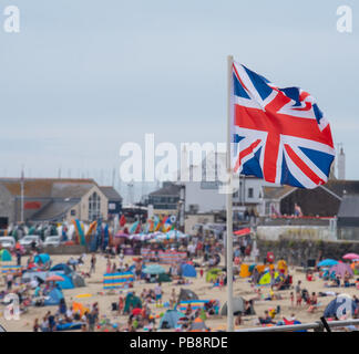Lyme Regis, Dorset, UK. 27th July 2018.  UK Weather: Hot and sticky in Lyme Regis.  British holidaymakers head to the seaside resort of Lyme Regis to enjoy the pretty beach as the UK swelters in hot and muggy tempertures.  The mercury is set to peak in parts of the UK today with 'Furnace Friday' bringing hot and thundery conditions. Credit: DWR/Alamy Live News Stock Photo