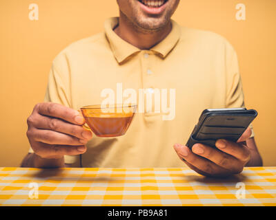 A young hipster man is drinking coffee and using smartphone Stock Photo