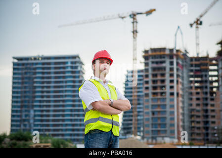 Proud architect on a construction site in front of buildings and cranes Stock Photo