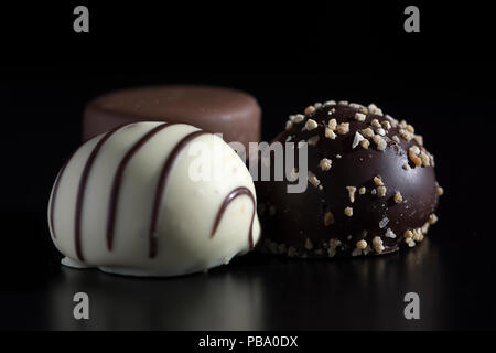Close up of three chocolate bonbons, white, dark and milk chocolate. Sweet, calorie-rich and energy-rich food with unhealthy and fattening qualities Stock Photo