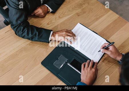 Top view of two business men signing contract papers on table. Hands of business executive signing documents in office. Stock Photo