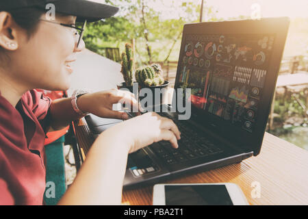 Asian fat teen using computer laptop to looking business information data chart for SME concepts. Stock Photo