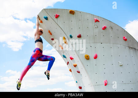 Photo of sporty woman in leggings hanging on wall for rock climbing against  blue sky with clouds in afternoon Stock Photo - Alamy