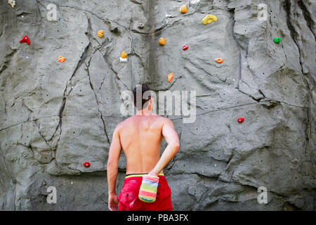 Photo from back of brunet climber on background of boulder for rock climbing during day Stock Photo