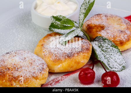 Delicious syrniki with cherries, jam and sour cream Stock Photo