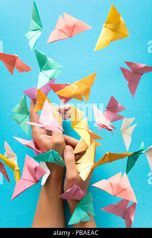 Mental health concept. Colorful paper butterflies flying and sitting on womans hands. Harmony emotion. Origami. Paper cut style. Stock Photo