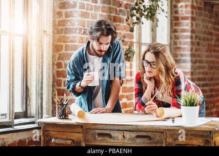 Team of young ambitious architects working together in a loft sunny office Stock Photo