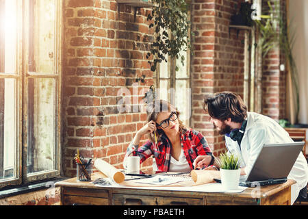 Two ambitious architects discussing construction project in loft modern office, they using laptop Stock Photo