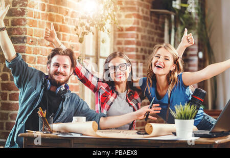 Happy young professional architects smiling to the camera during meeting in the loft modern office Stock Photo
