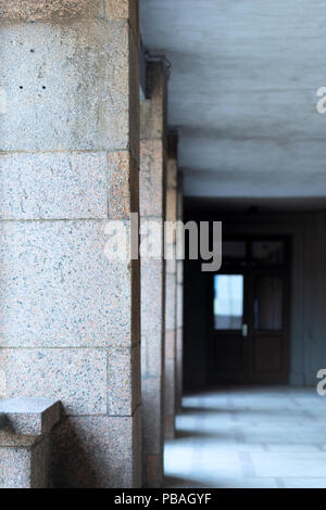 A row of columns with marble slabs on the walls leads to the door in perspective Stock Photo
