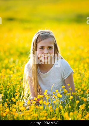 Outdoor portrait of a pretty teenage girl sitting in the buttercups. Stock Photo
