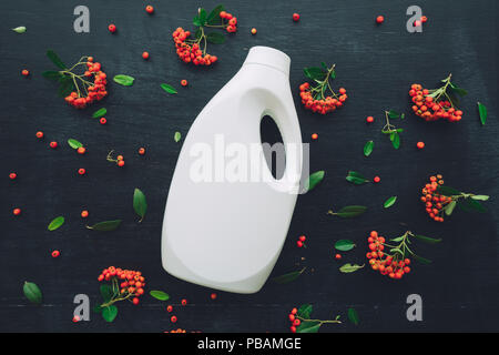 Flat lay liquid detergent plastic bottle container mock up top view on dark background decorated with wild berry fruit arrangement Stock Photo