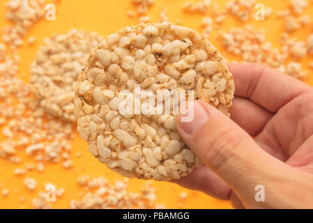 Rice cakes in male hand over yellow background, overhead view Stock Photo