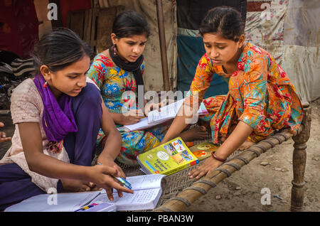 AHMEDABAD, INDIA - DECEMBER 10, 2017: Unidentified school girls of Indian Ethnicity sitting on cot doing homework with books and exercise notebooks. Stock Photo