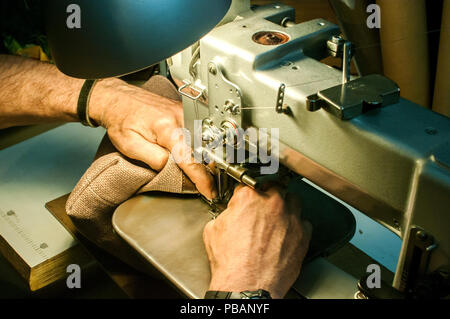 Leather tailor man hands making leather bag of sewing machine closeup as scene of working process Stock Photo