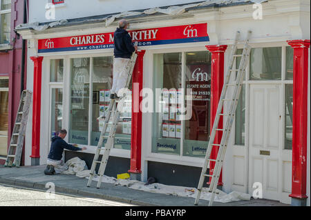 Painters and decorators repaint the front of an Estate Agents/Realtors in Skibbereen, West Cork, Ireland on a summer's day. Stock Photo