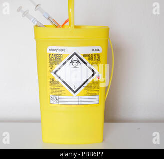 Yellow plastic box supplied to NHS patients to take home and put their used syringes into out of harm's way. The box gets returned to the hospital. Stock Photo