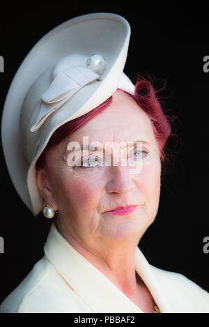 Detailed, close-up portrait: female re-enactor, smartly-dressed with tall posh hat, Black Country Museum 1940s event. Black background. Stock Photo