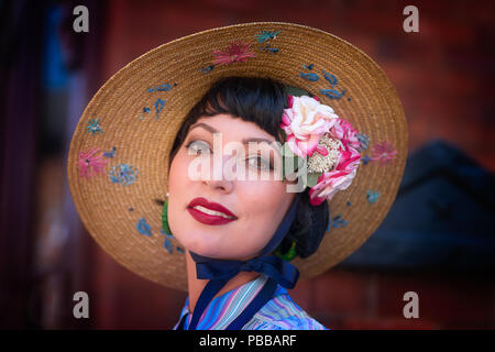 Close, front view portrait of attractive, chic, Caucasian female posing in pretty wide-brimmed hat, Black Country Museum, 1940s event. Stock Photo
