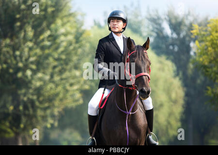 Young Chinese man riding horse Stock Photo