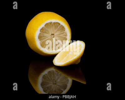 Fresh lemon fruit, sliced, on shiny black reflective background. Stock Photo