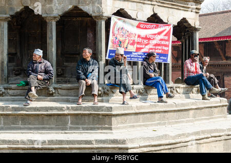 Men sitting and people watching at Chyasing Dewal, Patan Durbar Square, Nepal Stock Photo