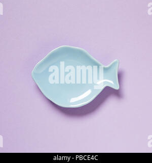 Fish shaped dish isolated on purple background Stock Photo