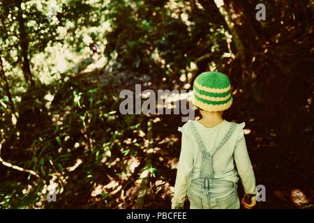 A child walks through a tropical rainforest, Nandroya Falls Circuit, Atherton Tablelands, QLD, Australia Stock Photo
