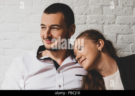 The girl and the guy in cafe, at a table, talk. The girl put the head on a shoulder to the guy. They smile. Stock Photo