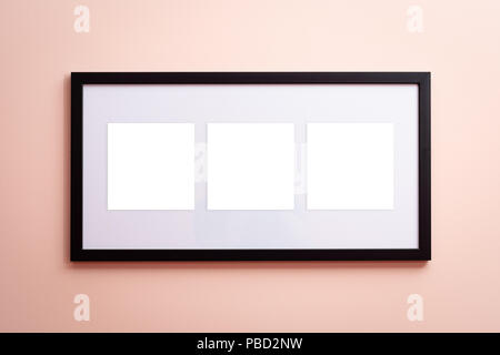 One blank canvas black border frame with three empty spaces on pink background on the wall Stock Photo