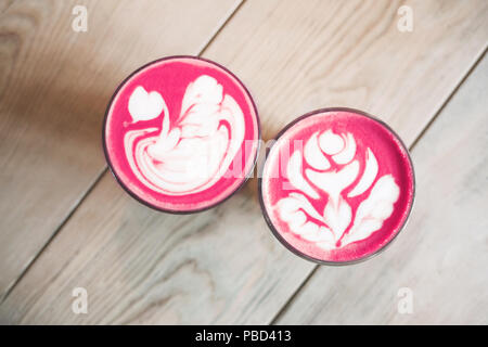 Healthy trendy beetroot latte with latte art in two glasses on wooden table. Top view. Stock Photo