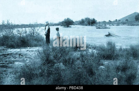 . English: A man and a boy standing next to the Santa Cruz River in Tucson, Arizona, during a flood, circa 1903. Sentinel Peak ('A' Mountain) is in the background at the right. circa 1903 1290 Santa Cruz River Flood Tucson Arizona Circa 1903 Stock Photo