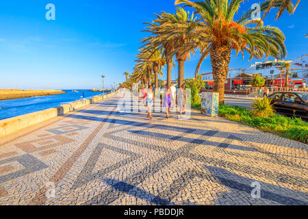 Lagos, Portugal - August 19, 2017: people walking along the Avenida dos Descobrimentos, the boulevard with palm trees on the port of Lagos. Lagos is p Stock Photo