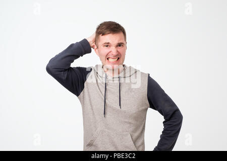 Suspicious middle aged european man looks doubtfully, being indecisive, makes grimace, tries to find solution. Stock Photo