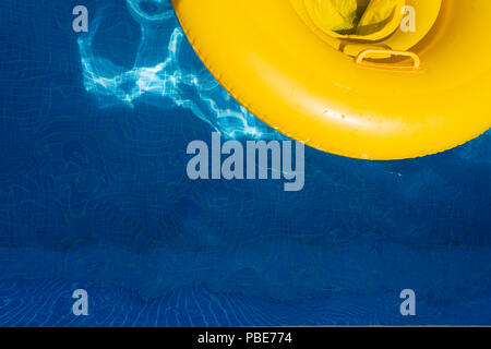 Yellow rubber ring floating in a pool with reflections in the water. Stock Photo