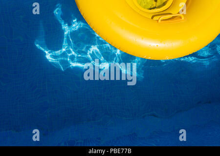 Yellow rubber ring floating in a pool with reflections in the water. Stock Photo