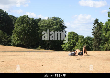 London UK. 28th July 2018. A sunbather enjoys the sunshine on the parched grass  on  Wimbledon Common with cooler temperatures forecast for the weekend after the hottest July day recorded on Friday Credit: amer ghazzal/Alamy Live News Stock Photo