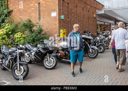 Calne, Wiltshire, UK, 28th July 2018  onlooker in front of bikes in pedestrian shopping centre at calne bike meet  Credit Estelle Bowden/Alamy live news Stock Photo