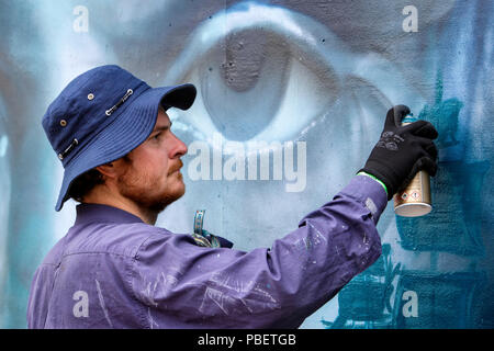 Bristol, UK. 28th July, 2018. An artist is pictured in South Street Park Bedminster as he starts creating his artwork for the festival. Upfest is Europe's largest free, street art & graffiti festival and is now in its tenth year. Credit: Lynchpics/Alamy Live News Stock Photo