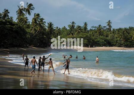 People palying in the surf at Hiriketiya Beach, Sri Lanka Stock Photo